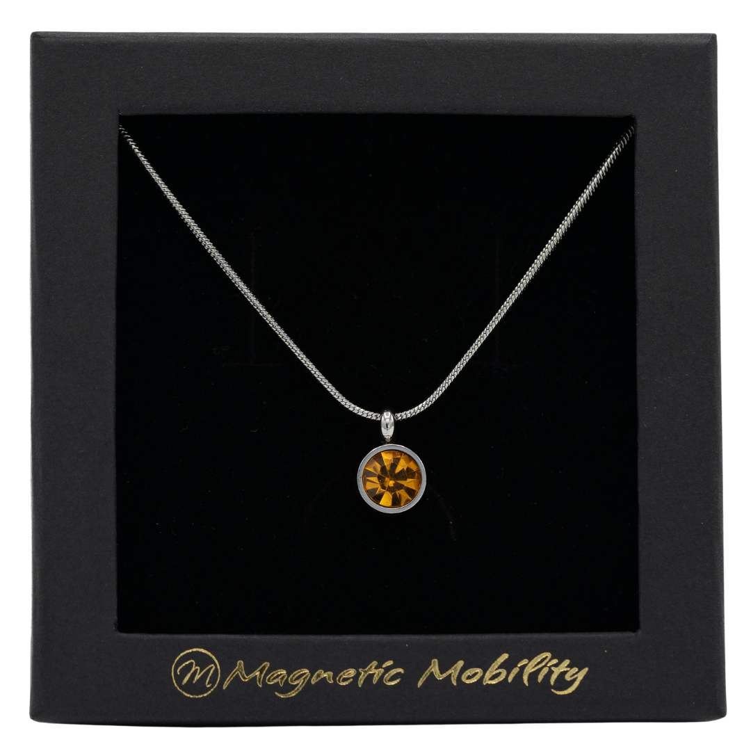 November Magnetic Mobility Birthstone Necklace featuring a Citrine Swarovski crystal pendant with a magnetic back. Ideal for relieving neck pain, displayed in a black box with Magnetic Mobility logo