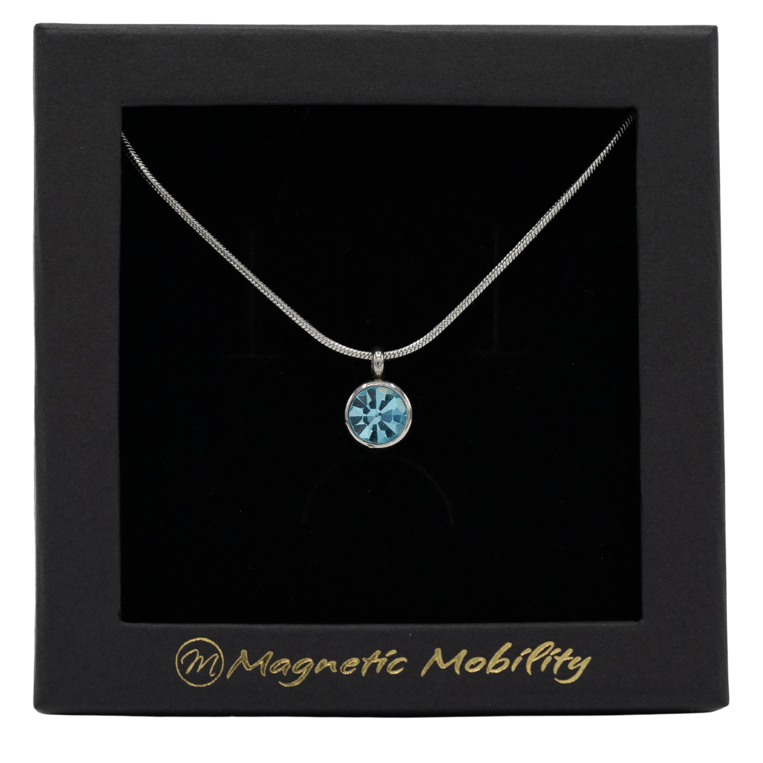 March Birthstone Necklace by Magnetic Mobility featuring a light blue Swarovski crystal pendant with a magnet. Perfect for neck pain relief, displayed in elegant black packaging.