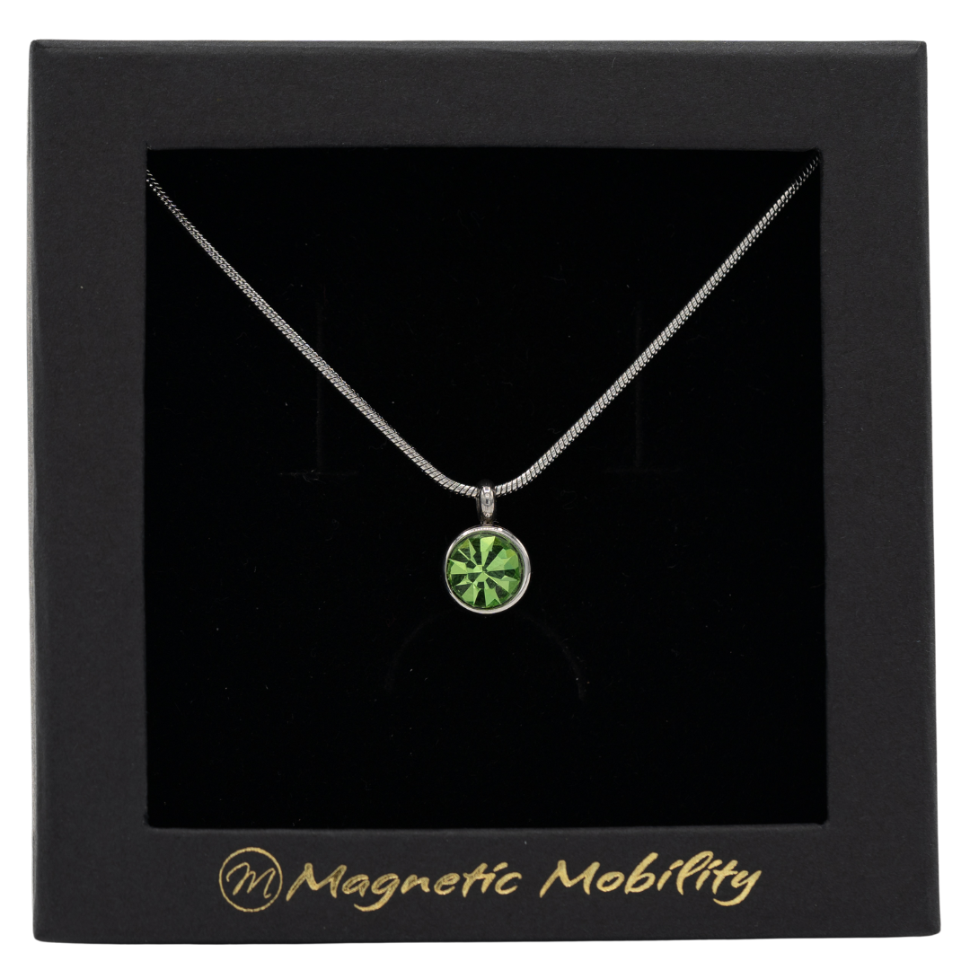 August Magnetic Mobility Birthstone Necklace showcasing a light green Swarovski crystal pendant. Provides relief from neck pain, elegantly presented in branded black packaging.