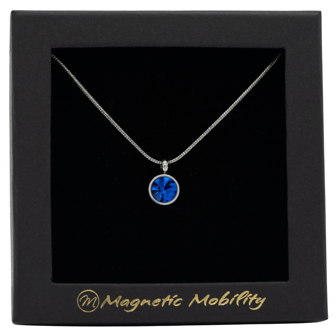 September Magnetic Mobility Birthstone Necklace with a blue Swarovski crystal pendant. Designed to help with neck pain relief, elegantly presented in black branded packaging.